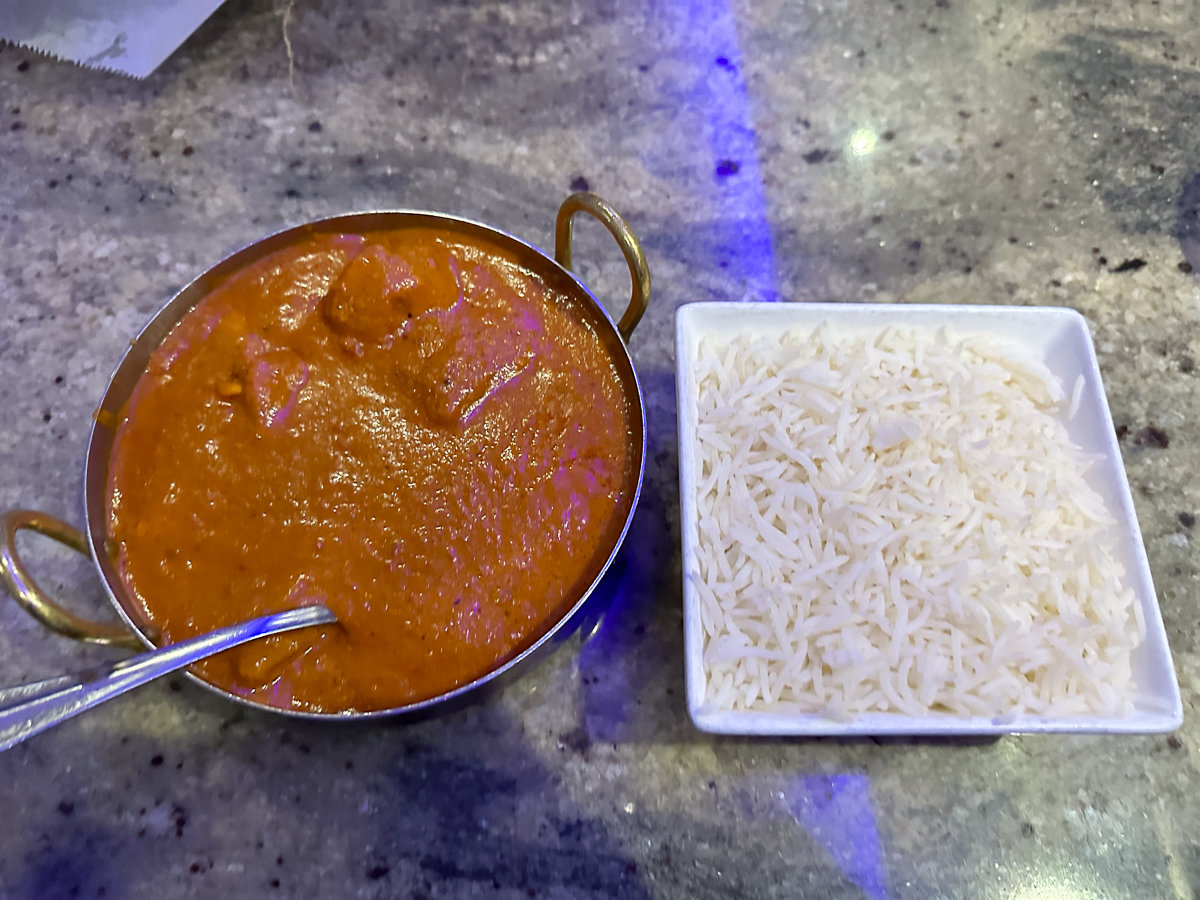 chicken in red sauce in a metal dish with white rice